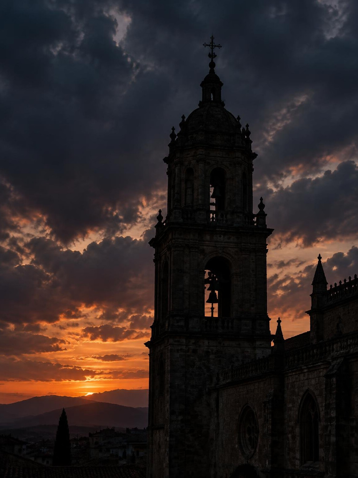 Old stone cathedral tower silhouette against a dramatic dusk sky