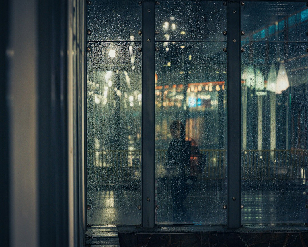 man reflecting in rainy window